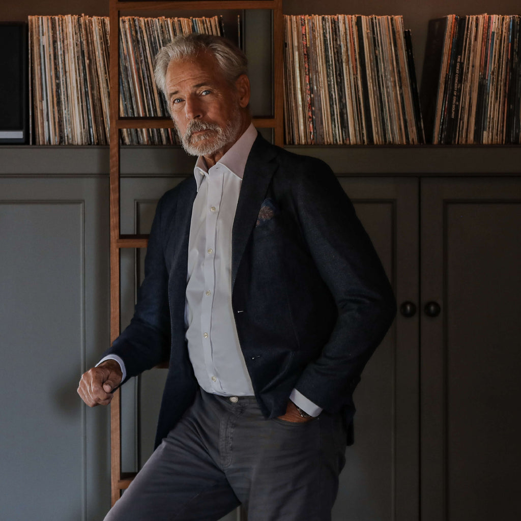 Model standing in front of bookcase wearinig white dress shirt and jacket 