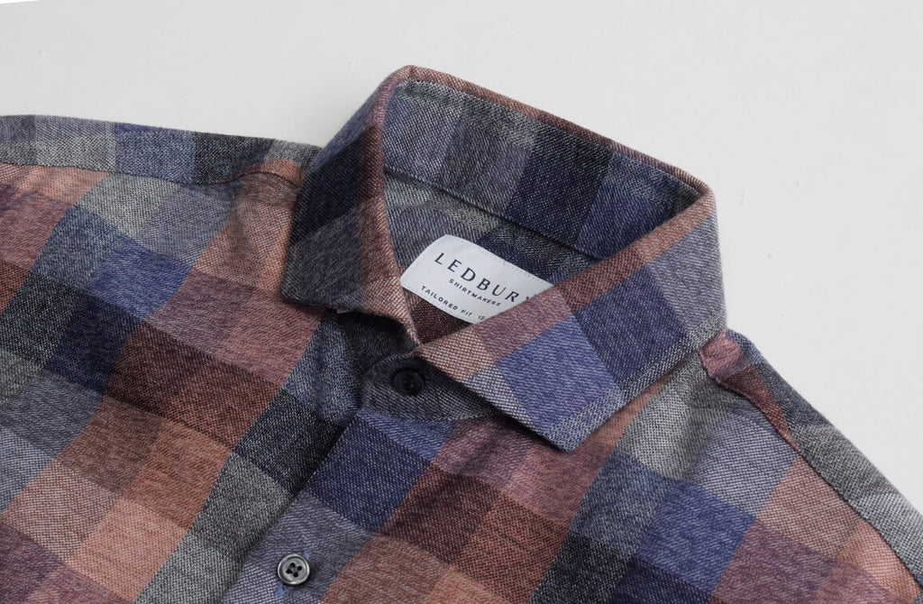 Closeup of the collar of a men's orange, blue and brown flannel button down shirt by Ledbury