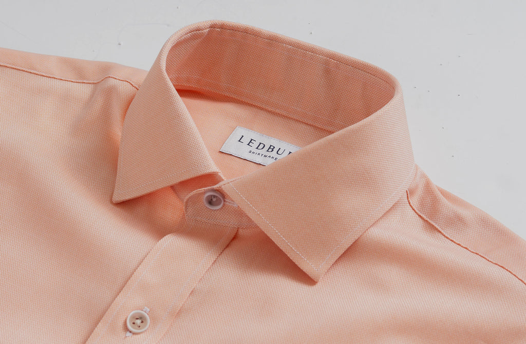 Closeup of the collar of a men's light orange herringbone dress shirt