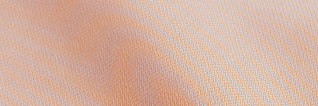 Closeup of the fabric of a men's light orange herringbone dress shirt